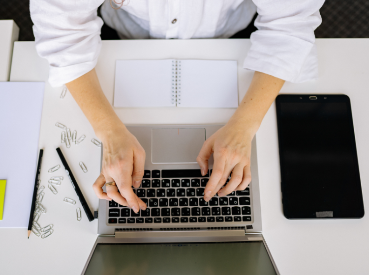 Overhead view of hands typing on a laptop.
